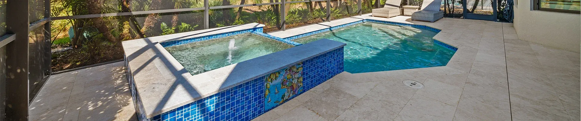 Spa with blue glass tile spillway and travertine deck