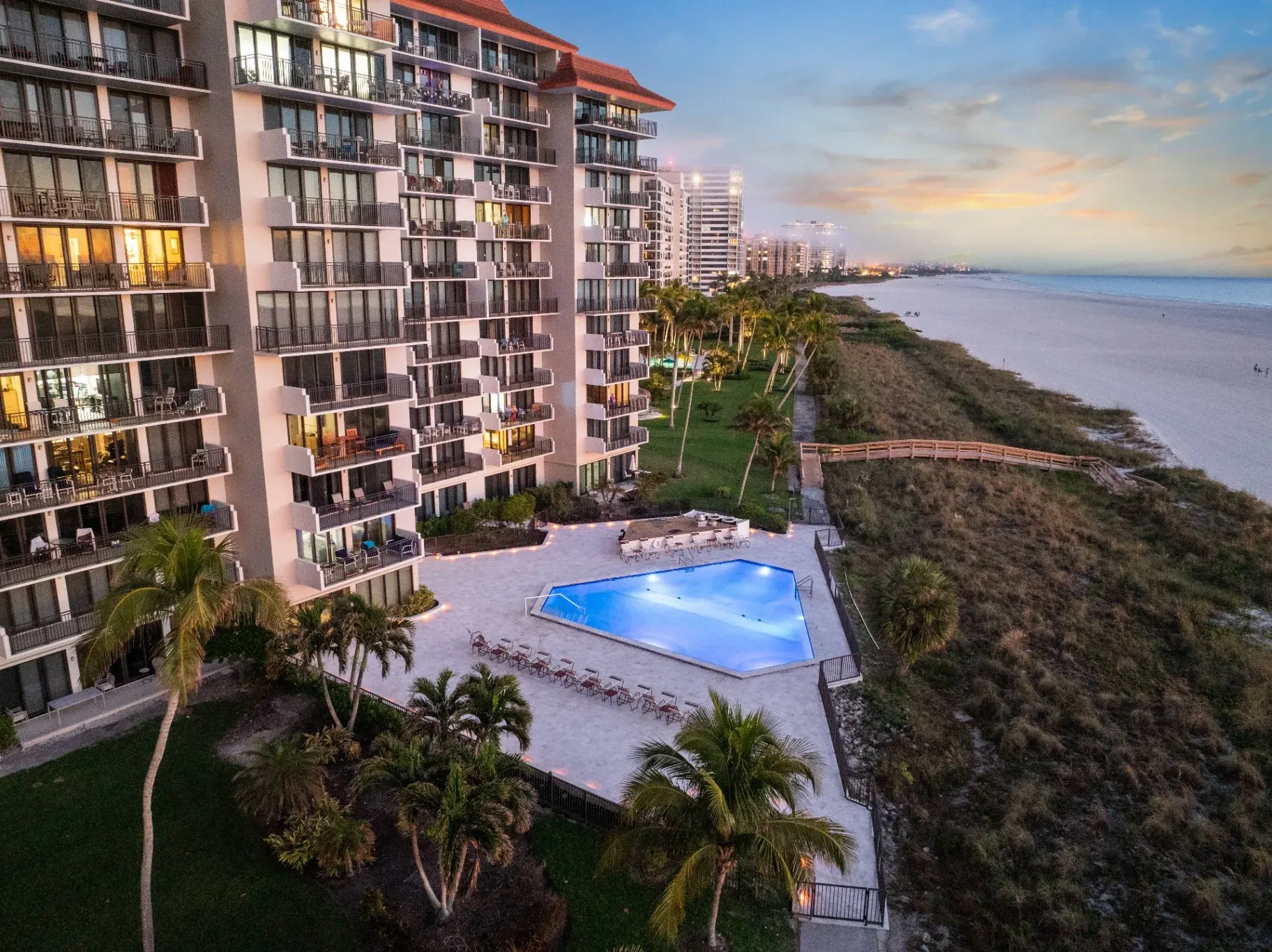 Beachfront condominium pool and travertine deck at dusk on Marco Island
